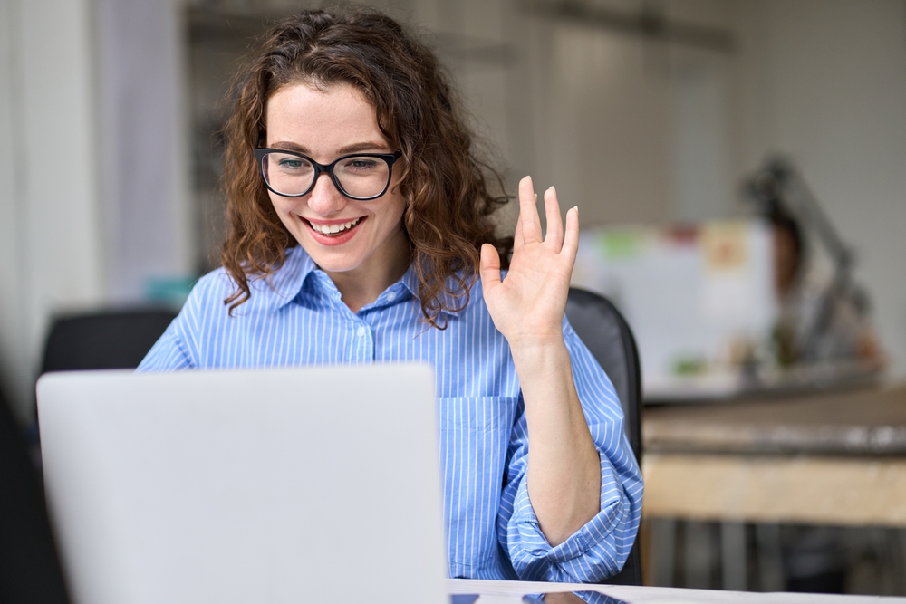 young,happy,business,woman,using,laptop,waving,hand,greeting,workers